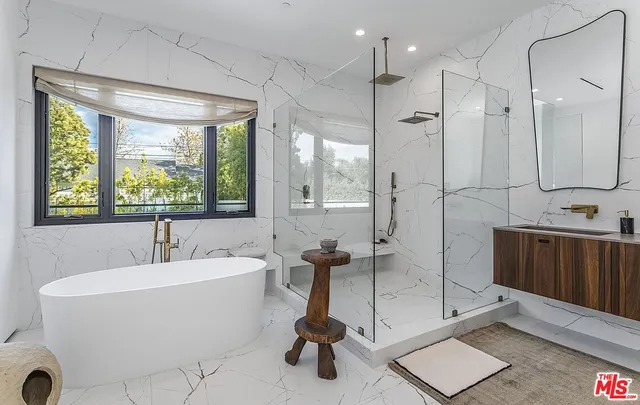 a bathroom with a tub a sink and a large mirror