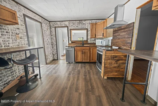 a kitchen with stainless steel appliances granite countertop a refrigerator a stove and a wooden floors