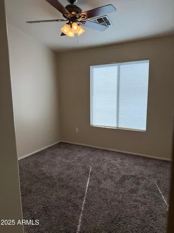 an empty room with a window and chandelier fan