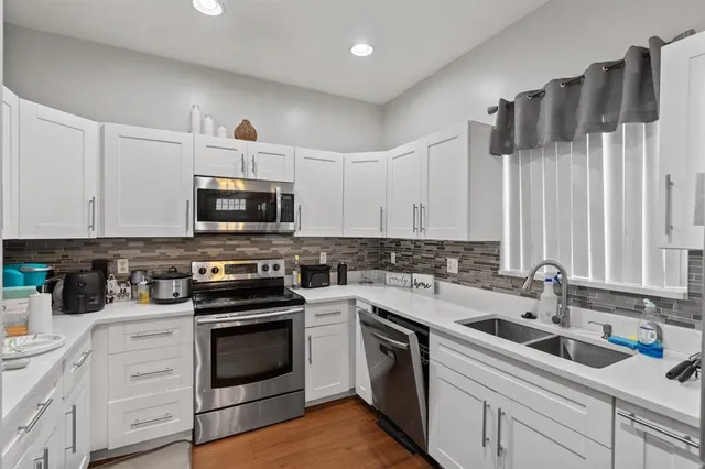 a kitchen with white cabinets and appliances