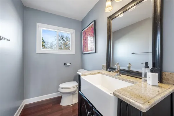 a bathroom with a granite countertop toilet a sink and a mirror