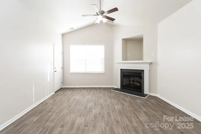 an empty room with wooden floor a fireplace and a window