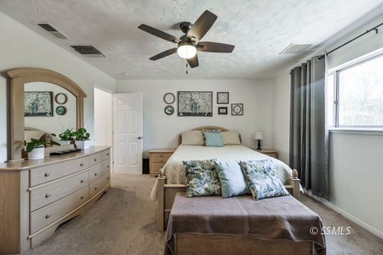 1233 Mayo Street Ridgecrest, CA 93555 - Photo 26 of 32 a bedroom with a large bed and a chandelier