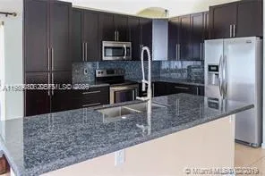 a kitchen with stainless steel appliances granite countertop a refrigerator and a sink