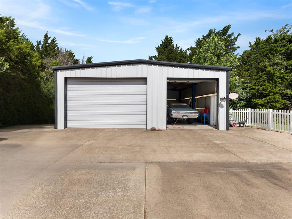 401 Rugged Drive Red Oak, TX 75154 - Photo 4 of 40 Two-bay metal garage structure featuring a roll-up door and an open bay with a lift system