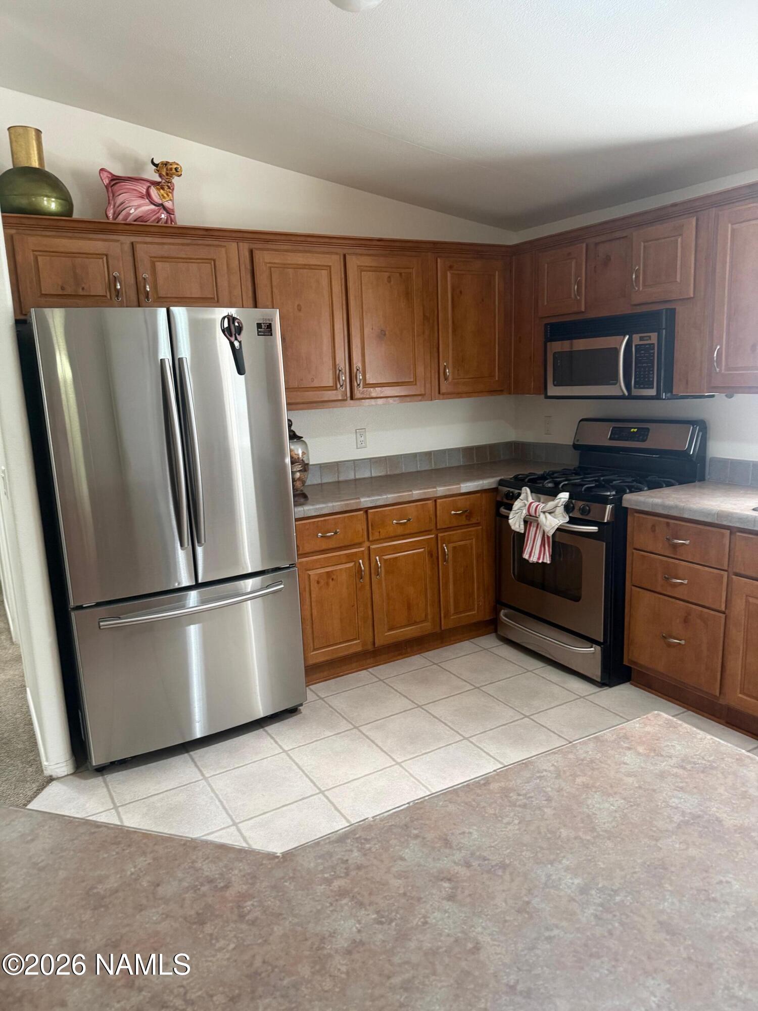 17075 Grizzly Ridge Munds Park, AZ 86017 - Photo 11 of 31 a kitchen with stainless steel appliances granite countertop a refrigerator a stove a sink and a microwave