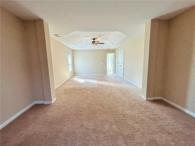 an empty room with windows and ceiling fan