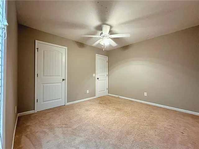 an empty room with a chandelier fan and closet