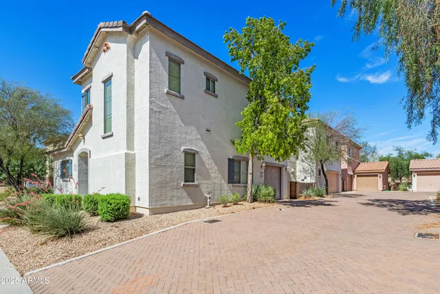 a view of a white house with large windows and a small yard