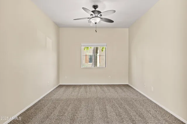 an empty room with windows and fan