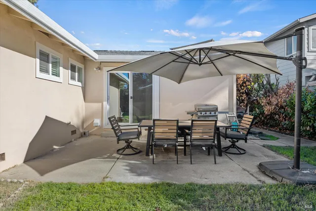 a view of a patio with table and chairs under an umbrella