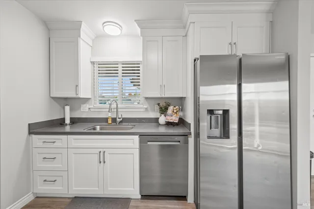 a kitchen with cabinets stainless steel appliances a sink and a window