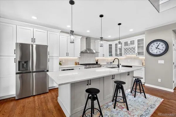 a kitchen with stainless steel appliances granite countertop a refrigerator a sink a stove a dining table and chairs