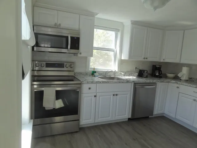 a kitchen with granite countertop white cabinets stainless steel appliances and window