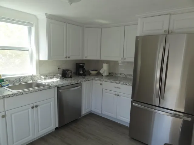 a kitchen with stainless steel appliances granite countertop a refrigerator sink and white cabinets