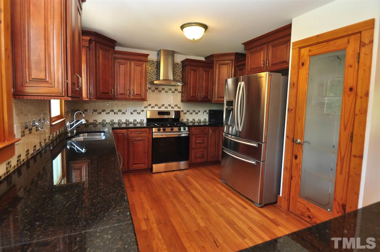 738 Castle Rock Farm Road Pittsboro, NC 27312 - Photo 5 of 25 a kitchen with stainless steel appliances granite countertop a refrigerator a sink dishwasher a stove with wooden cabinets and floor