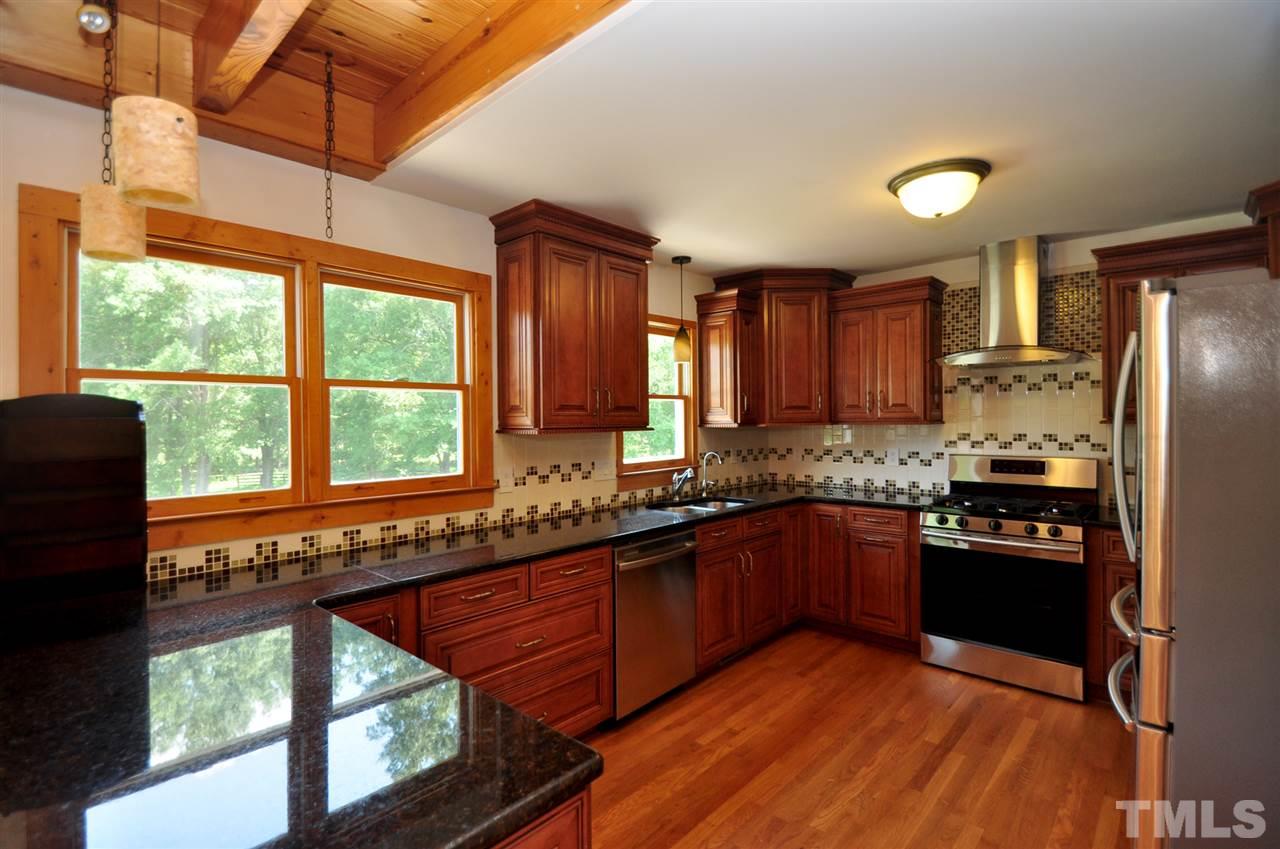 738 Castle Rock Farm Road Pittsboro, NC 27312 - Photo 6 of 25 a kitchen with stainless steel appliances granite countertop a refrigerator a sink dishwasher a stove top oven and a dining table with wooden floor