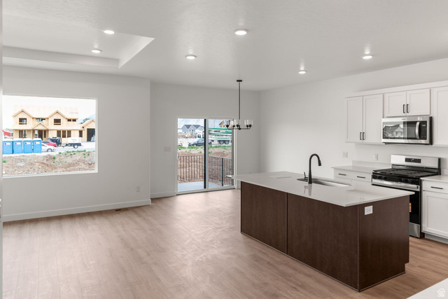 1417 West 2350th South, Unit 14 Perry, UT 84302 - Photo 4 of 19 Modern kitchen featuring a dark wood-finish island with integrated sink, white countertops, and white cabinetry