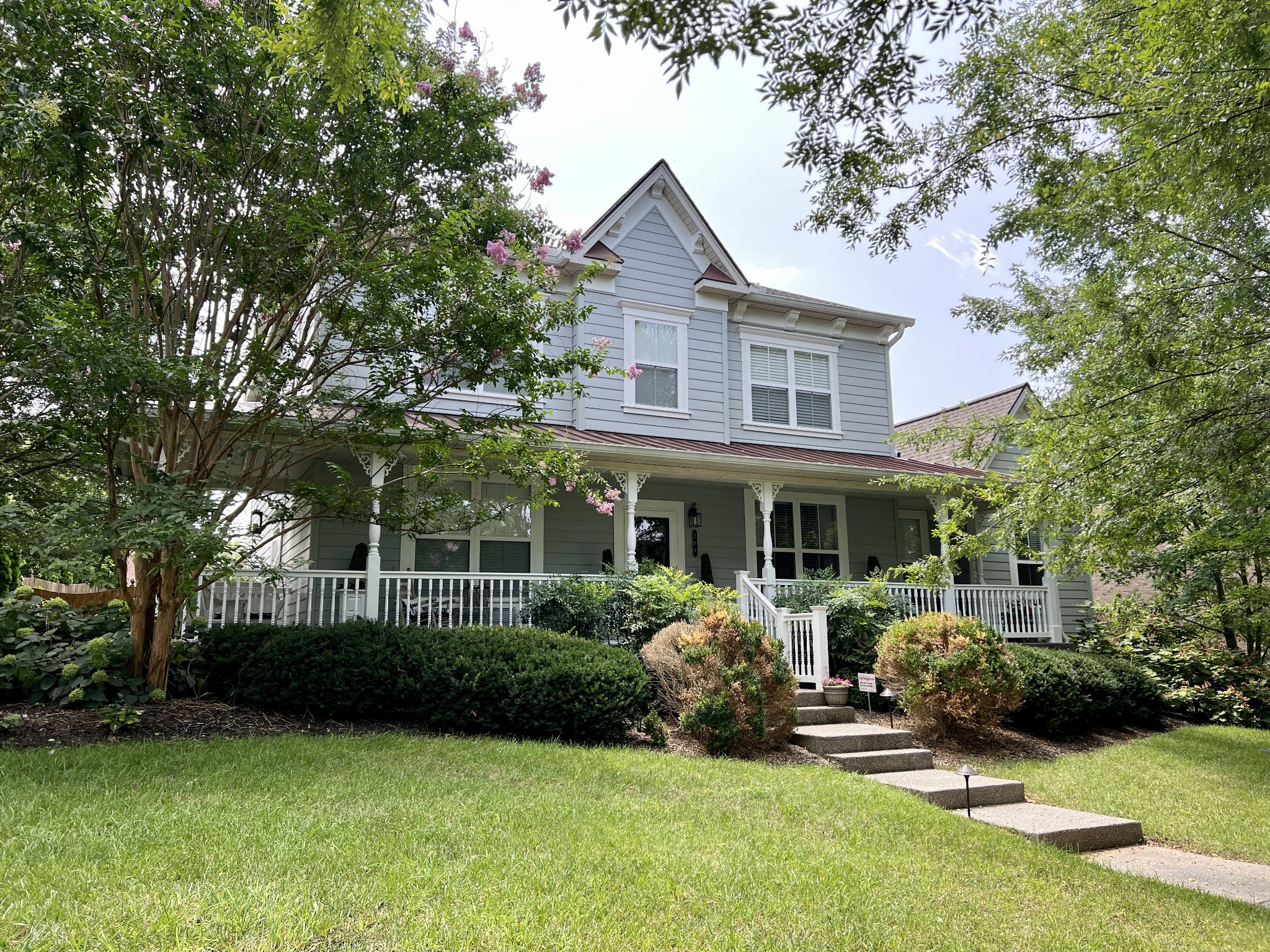 a front view of a house with a garden and trees