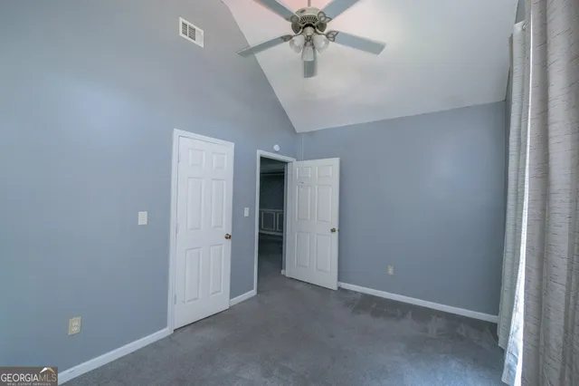 an empty room with closet and a chandelier fan