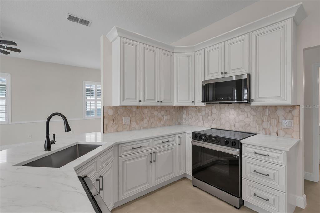 2626 Raccoon Run Lane Orlando, FL 32837 - Photo 19 of 62 a kitchen with white cabinets stainless steel appliances and sink