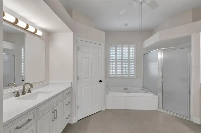 an empty room with wooden floor ceiling fan and windows