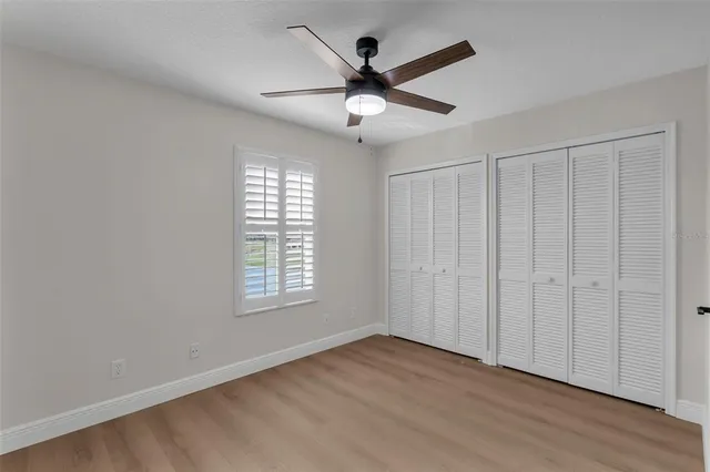 an empty room with wooden floor fan and windows