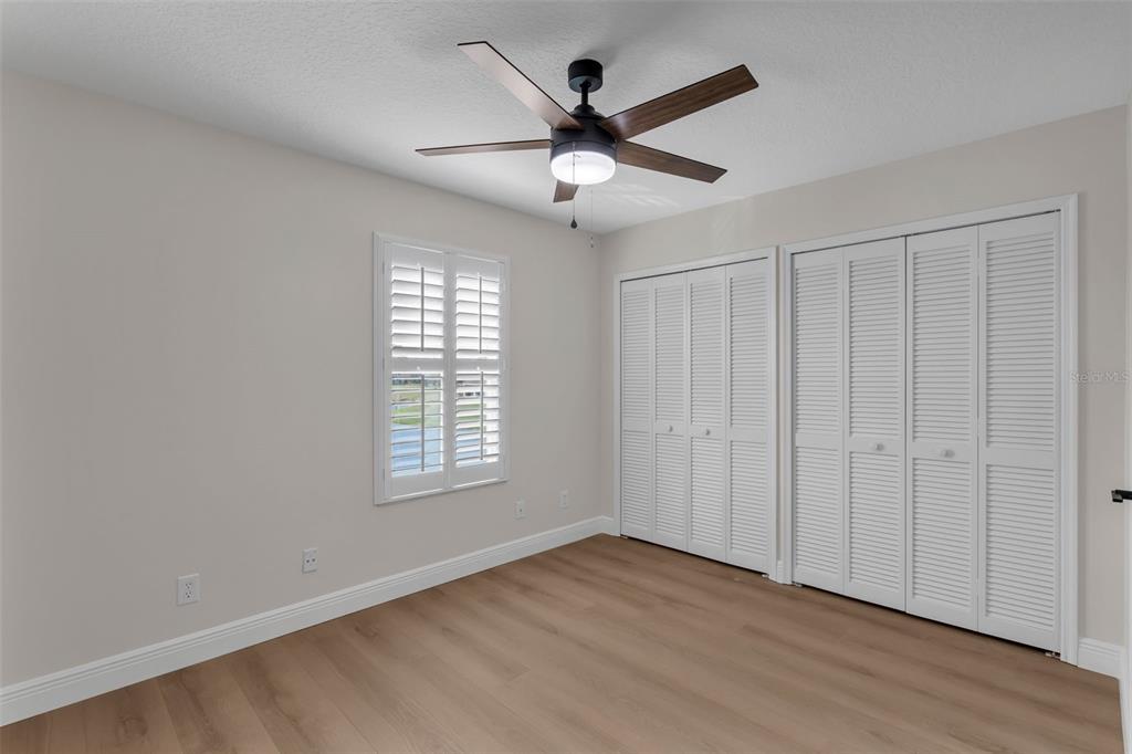 2626 Raccoon Run Lane Orlando, FL 32837 - Photo 32 of 62 an empty room with wooden floor ceiling fan and windows