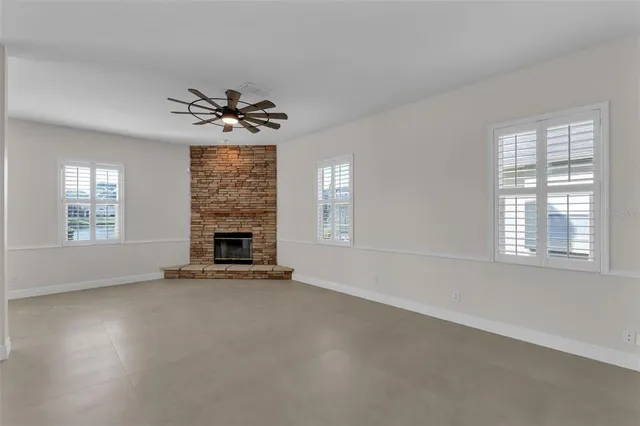an empty room with windows and fireplace