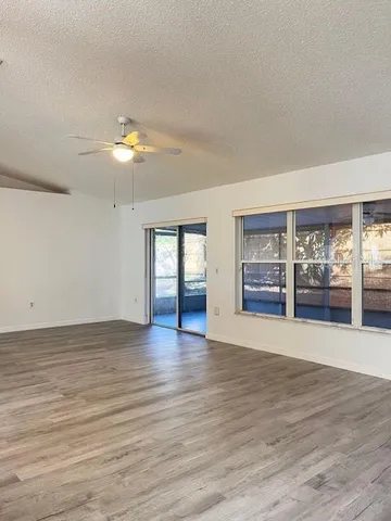 a view of an empty room with a window and wooden floor
