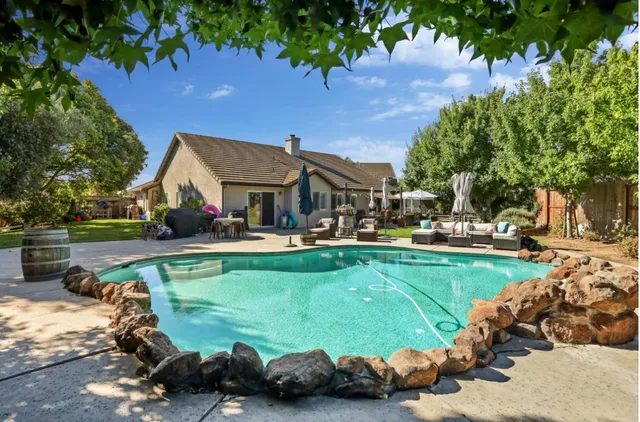a view of a swimming pool with lawn chairs and a big yard