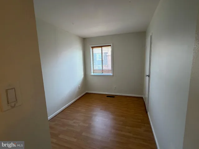 an empty room with wooden floor and window
