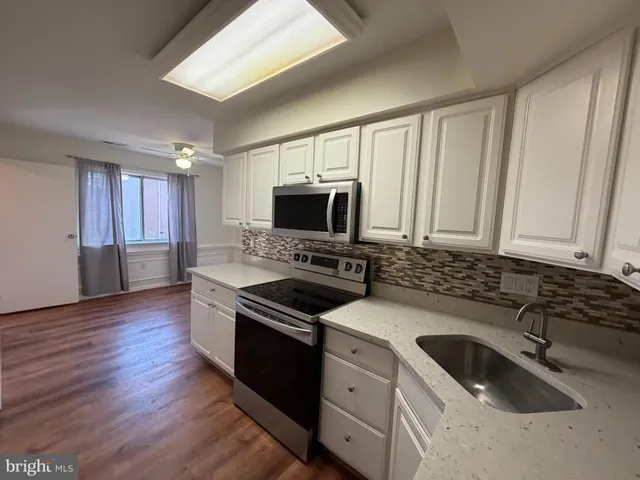 a kitchen with granite countertop a sink cabinets and stainless steel appliances