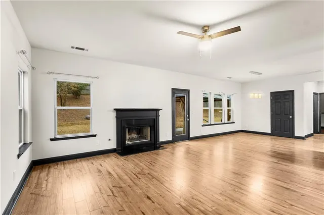 wooden floor in an empty room with a fireplace and a window