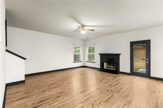 a view of an empty room with wooden floor fireplace and a window