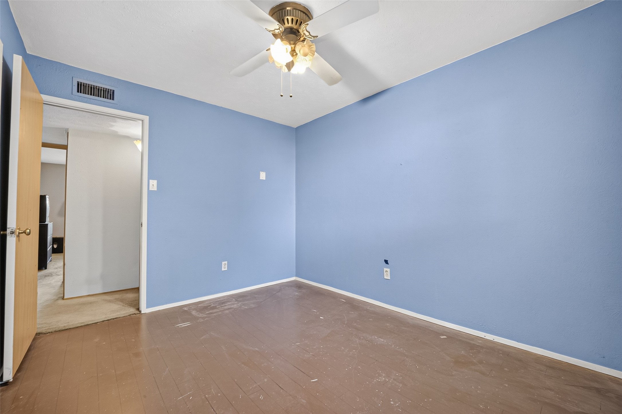 22926 Millgate Drive Spring, TX 77373 - Photo 23 of 34 This room features light blue walls, a ceiling fan with a light fixture, and a wood or laminate floor. It has an open door leading to a carpeted area, providing a blank canvas for personalization.
