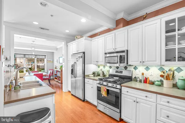 a kitchen with stainless steel appliances kitchen island granite countertop a refrigerator a stove and white cabinets with wooden floors