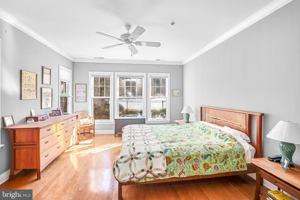a bedroom with a bed a dresser and wooden floor