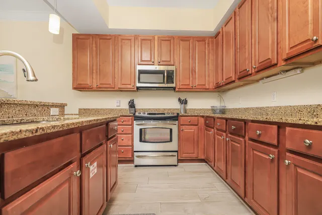 a kitchen with granite countertop wooden cabinets and white appliances