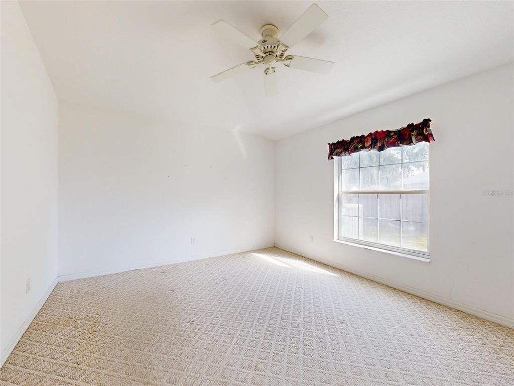 7558 Southwest 103rd Loop Ocala, FL 34476 - Photo 19 of 38 an empty room with a chandelier fan and windows