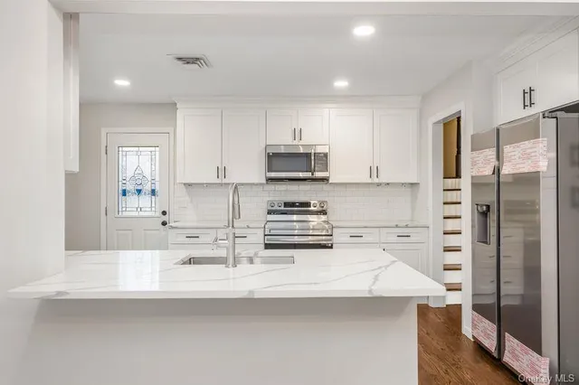 a kitchen with kitchen island a sink stainless steel appliances and cabinets
