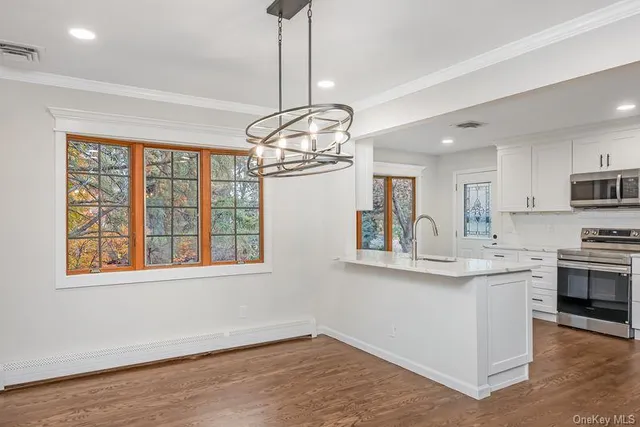 a kitchen with stainless steel appliances granite countertop a stove and a view of living room