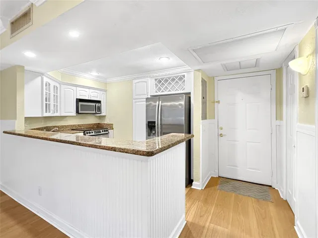 a view of a kitchen with stainless steel appliances granite countertop a sink and cabinets