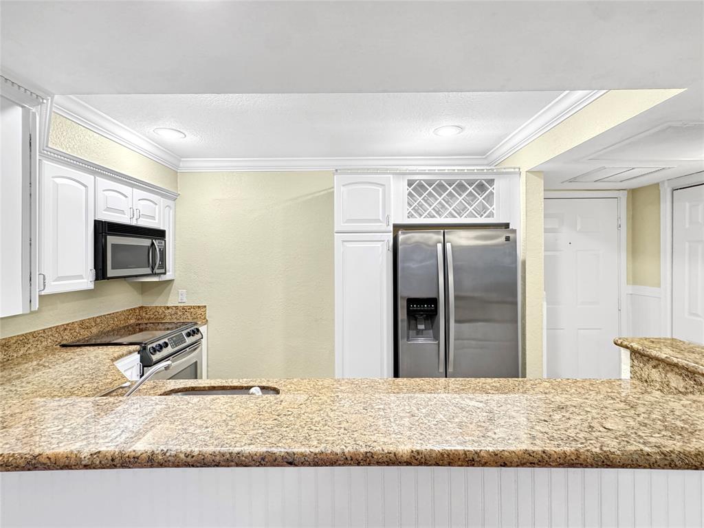 1515 East Broward Boulevard, Unit 107 Fort Lauderdale, FL 33301 - Photo 8 of 36 Gourmet kitchen features granite counters, breakfast bar seating, and a built-in wine rack for effortless entertaining.