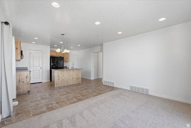 1218 Moonlight Drive Elk Ridge, UT 84651 - Photo 6 of 44 Kitchen with a kitchen island with sink, light wood finish cabinetry, a chandelier, light stone countertops, and stone finish flooring