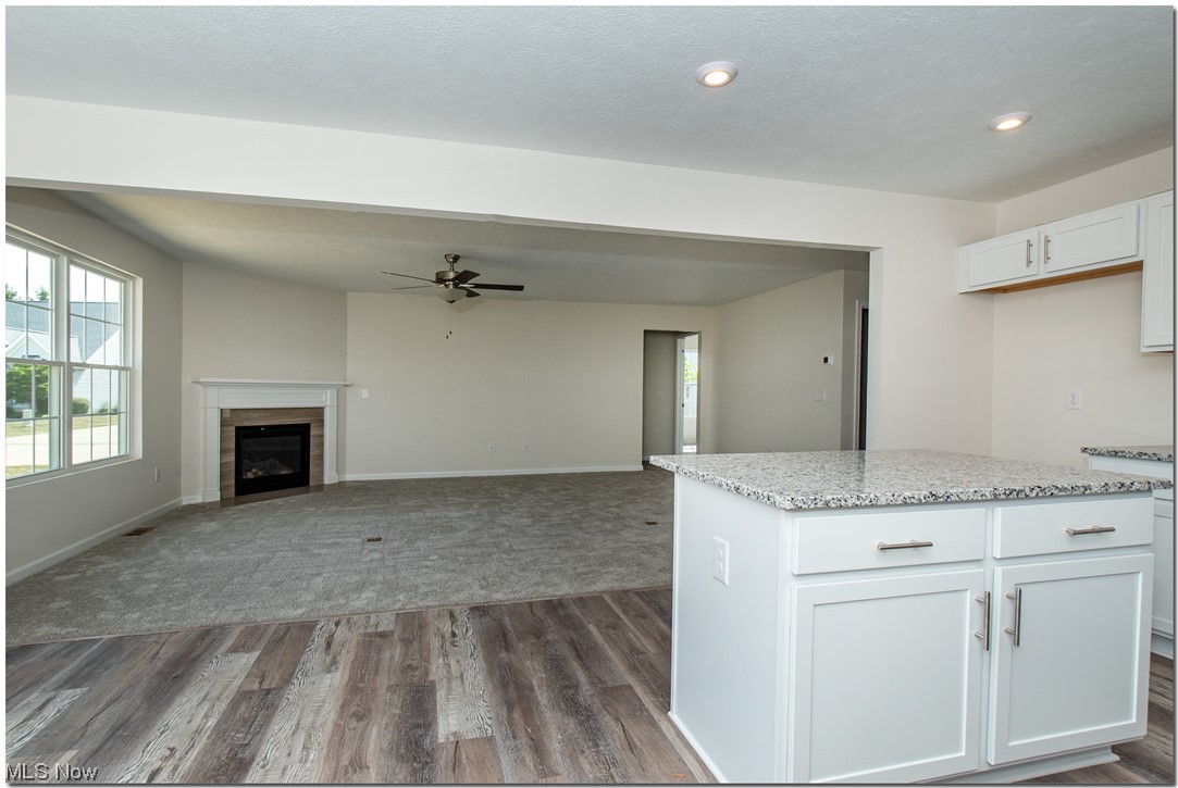 7701 Webster Road Middleburg Heights, OH 44130 - Photo 26 of 29 Kitchen with white cabinetry, a tile fireplace, dark colored carpet, light stone counters, and ceiling fan