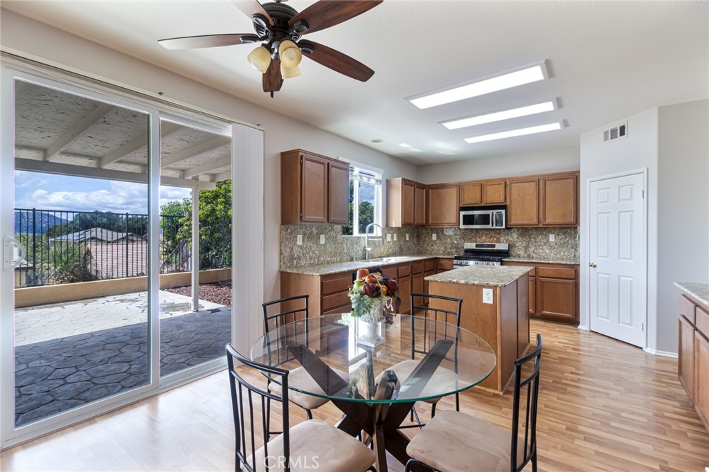 46321 Sharon Street Temecula, CA 92592 - Photo 12 of 40 a kitchen with stainless steel appliances kitchen island granite countertop a refrigerator a stove a sink with island chairs and wooden floor