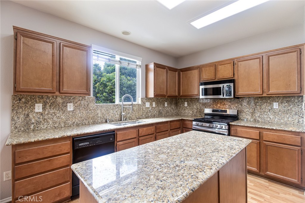 46321 Sharon Street Temecula, CA 92592 - Photo 14 of 40 a kitchen with stainless steel appliances granite countertop wooden cabinets a stove top oven a sink and dishwasher with wooden floor