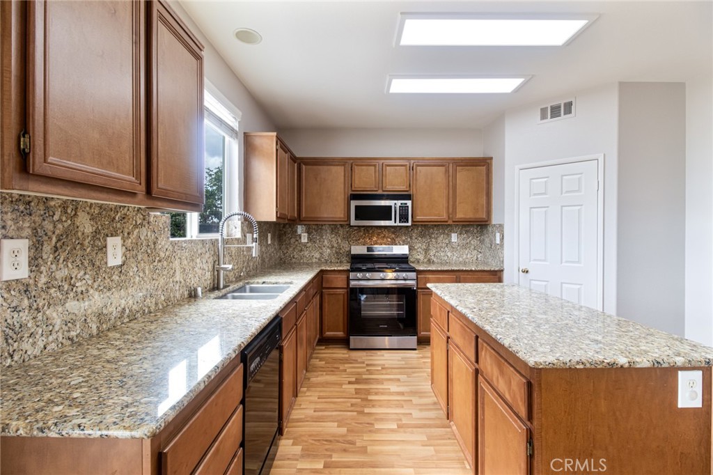 46321 Sharon Street Temecula, CA 92592 - Photo 15 of 40 a kitchen with granite countertop a sink a counter top space appliances and cabinets