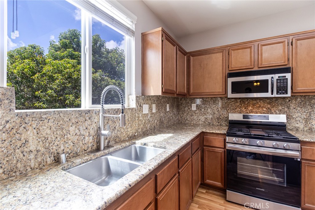 46321 Sharon Street Temecula, CA 92592 - Photo 16 of 40 a kitchen with granite countertop a sink stove and microwave